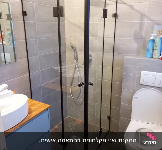 מקלחון זכוכית עם ראש מקלחת וכיור לידו